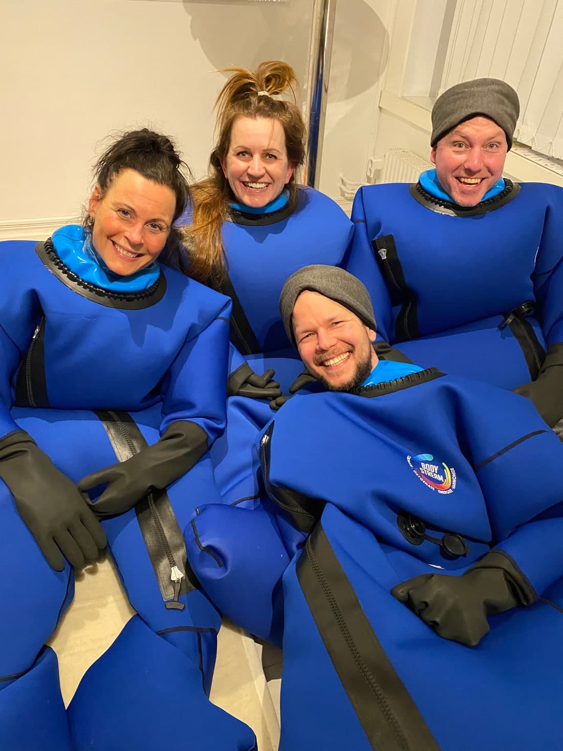 A group of four smiling BodyStream users together in the blue CO2 therapy suits